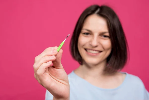 Schöne glückliche junge Frau mit Interdentalbürste auf rosa Hintergrund — Stockfoto