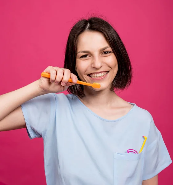 Schöne glückliche junge Frau mit Zahnbürste auf leerem rosa Hintergrund — Stockfoto