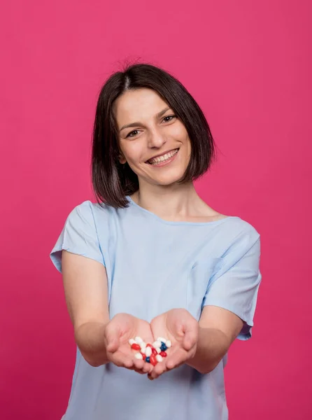 Schöne junge Frau hält viele Pillen in ihren Händen — Stockfoto