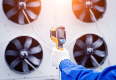 Teknisyen, yoğunlaştırma ünitesi ısı değiştiricisini kontrol etmek için termal görüntüleme kızılötesi termometresi kullanıyor..