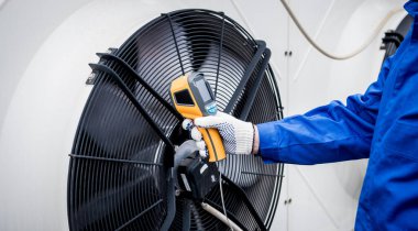 Teknisyen, yoğunlaştırma ünitesi ısı değiştiricisini kontrol etmek için termal görüntüleme kızılötesi termometresi kullanıyor..