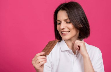 Güzel genç bir kadın elinde bir çikolata çubuğu tutuyor.