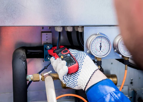 Teknisyen akım kıskaçlarıyla ısı değiştiricisinin güç kablolarını kontrol ediyor. — Stok fotoğraf