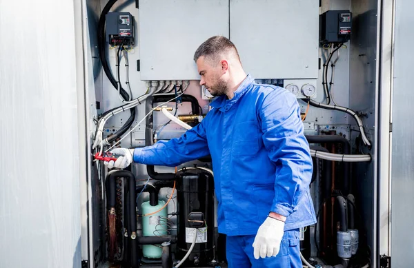 El técnico comprueba las líneas eléctricas del intercambiador de calor con abrazaderas de corriente —  Fotos de Stock