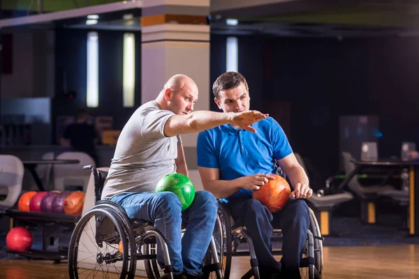 Dos jóvenes discapacitados en sillas de ruedas jugando bolos en el club —  Fotos de Stock
