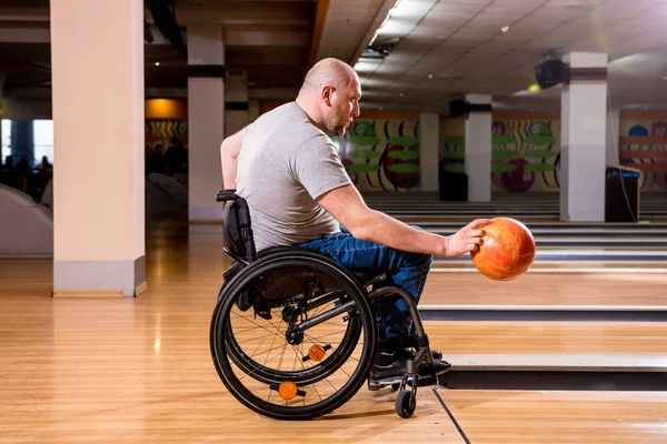 Joven discapacitado en silla de ruedas jugando bolos en el club —  Fotos de Stock