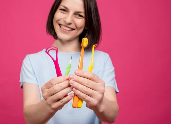 Beautiful young woman uses an oral care kit consisting of a tongue scraper, single tufted and interdental brush — Stock Photo, Image
