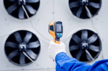 Teknisyen, yoğunlaştırma ünitesi ısı değiştiricisini kontrol etmek için termal görüntüleme kızılötesi termometresi kullanıyor..