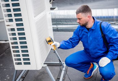 Teknisyen, yoğunlaştırma ünitesi ısı değiştiricisini kontrol etmek için termal görüntüleme kızılötesi termometresi kullanıyor..