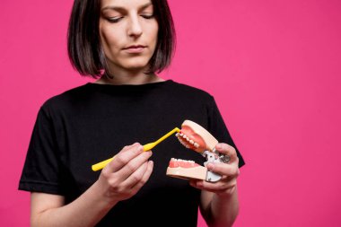 Güzel, mutlu, pembe arka planda tek telli diş fırçası olan genç bir kadın.