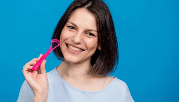 Schöne glückliche junge Frau mit Zungenschaber auf blauem Hintergrund — Stockfoto