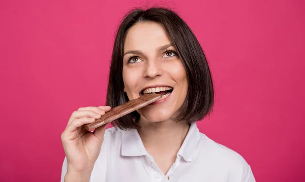 Mulher bonita morde uma barra de chocolate. — Fotografia de Stock