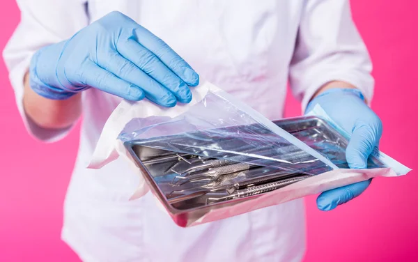 Kvinde tandlæge åbner en pakke af sterile tandinstrumenter - Stock-foto