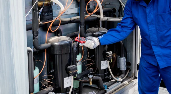 El técnico comprueba las líneas eléctricas del intercambiador de calor con abrazaderas de corriente —  Fotos de Stock