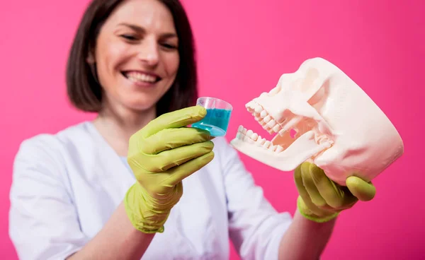 Beautiful girl proposes mouthwash for artificial skull — Stock Photo, Image