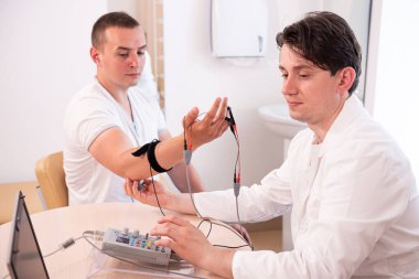 Tıbbi merkezde elektromiyografi kullanan hasta sinirleri test ediliyor.