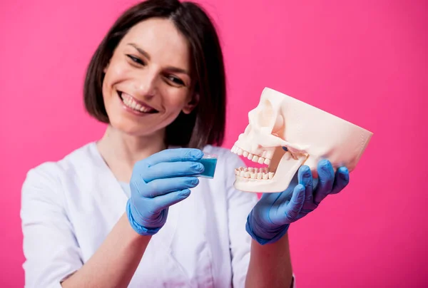 Beautiful girl proposes mouthwash for artificial skull — Stock Photo, Image