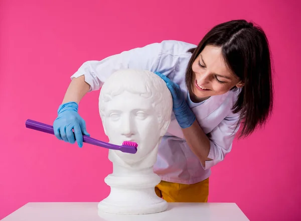 Femme dentiste brossant les dents d'une statue antique à l'aide d'une grande brosse à dents — Photo