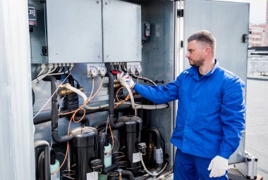 Teknisyen akım kıskaçlarıyla ısı değiştiricisinin güç kablolarını kontrol ediyor.