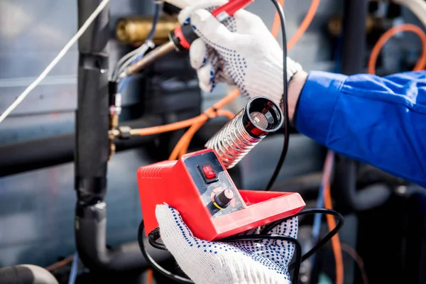 El técnico repara sensores electrónicos de temperatura con un soldador electrónico —  Fotos de Stock