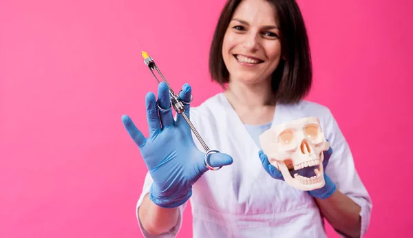 Woman dentist with a carpool syringe injects anesthetic into the gum of the artificial skull — Stock Photo, Image