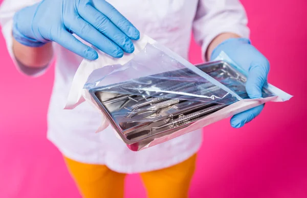 Kvinde tandlæge åbner en pakke af sterile tandinstrumenter - Stock-foto