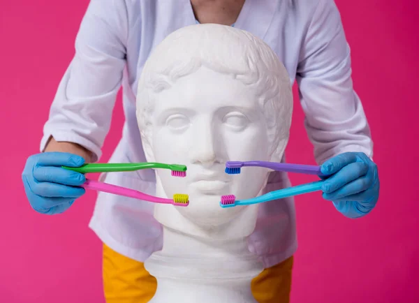 Zahnärztin beim Zähneputzen einer antiken Statue mit vier Zahnbürsten — Stockfoto