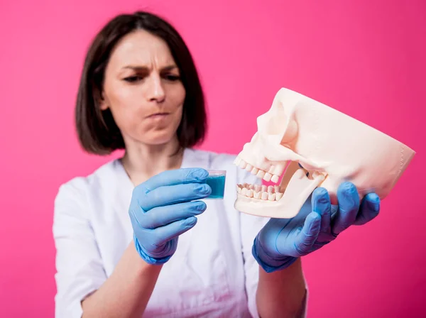 Beautiful girl proposes mouthwash for artificial skull — Stock Photo, Image
