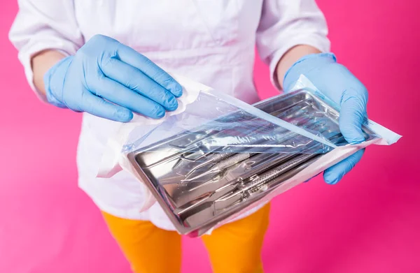 Woman dentist opens a package of sterile dental instruments — Stock Photo, Image