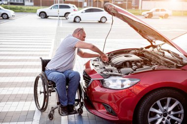 Tekerlekli sandalyedeki engelli adam, arabasını park yerinde kontrol et.