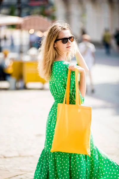 Jonge mooie vrouw met geel linnen eco tas op stad achtergrond. — Stockfoto