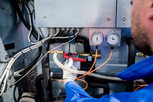 Teknisyen akım kıskaçlarıyla ısı değiştiricisinin güç kablolarını kontrol ediyor. — Stok fotoğraf