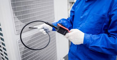 Teknisyen, ısı değiştiricinin tıkanmasını kontrol etmek için dijital kamera kullanıyor.