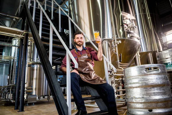 Jonge mannelijke brouwer in lederen schort in moderne brouwerij fabriek — Stockfoto