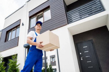 Genç teslimatçı elinde bir karton kutu tutuyor.