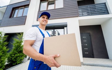Genç teslimatçı elinde bir karton kutu tutuyor.