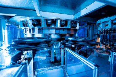 Modern içecek fabrikasında otomatik doldurma makinesi plastik PET şişelerine su doldurur.