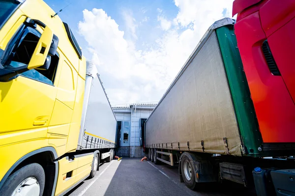 Grote vrachtwagens in de buurt van magazijn tegen blauwe lucht achtergrond — Stockfoto