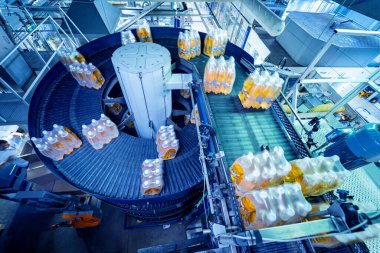 İçecek fabrikasında ambalaj hattı için modern bağlama ve taşıma makinesi.