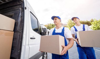 İki nakliye şirketi çalışanı bir minibüse kutu ve mobilya yüklüyorlar..
