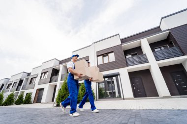 İki nakliye şirketi çalışanı yeni müşterilerin evlerine kutu indiriyor.