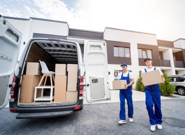 İki nakliye şirketi çalışanı bir minibüse kutu ve mobilya yüklüyorlar..