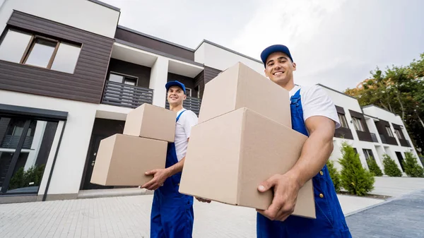 Zwei Mitarbeiter eines Umzugsunternehmens laden Kisten bei Neukunden ab — Stockfoto