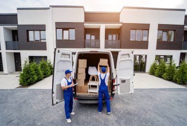 İki nakliye şirketi çalışanı bir minibüse kutu ve mobilya yüklüyorlar..