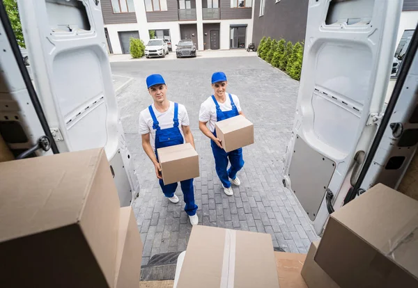 Zwei Mitarbeiter einer Umzugsfirma laden Kisten in einen Kleinbus. — Stockfoto
