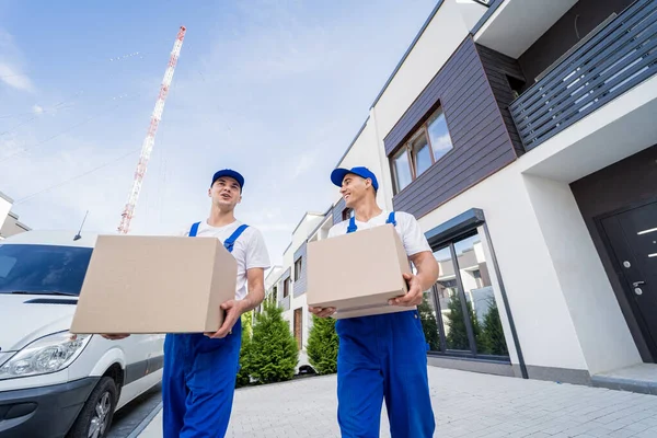 Zwei Mitarbeiter einer Umzugsfirma entladen Kisten aus Kleinbus in die Wohnung der Kunden — Stockfoto