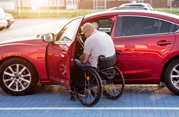 Unga handikappade förare sätter sig i röd bil fom rullstol — Stockfoto