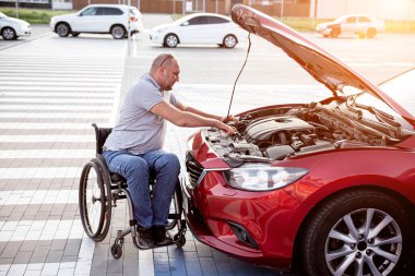 Tekerlekli sandalyedeki engelli adam, arabasını park yerinde kontrol et.