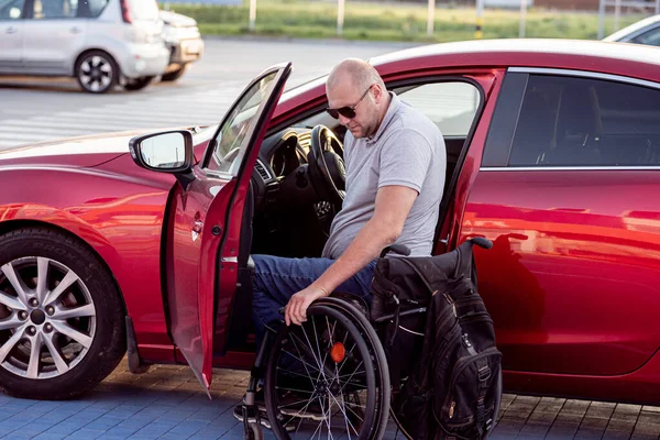Unga handikappade förare sätter sig i röd bil fom rullstol — Stockfoto