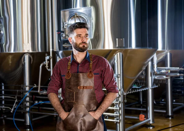 Jonge mannelijke brouwer in lederen schort in moderne brouwerij fabriek — Stockfoto